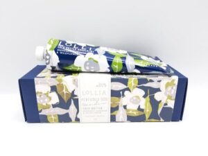 A tube of LOLLIA PERFUMED HAND CREME With Shea Butter, MIDNIGHT GARDENS& WILDFLOWER BY MARGOT ELENA 4 oz in a blue and white box.